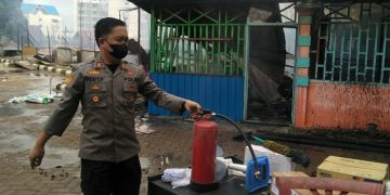 Kapolsek Jaluko terlihat sedang memegang tabung racun api untuk membantu menjinakan si jago merah yang menghanguskan 5 kantin di kampus UIN STS Jambi, Selasa (27/12/2022). [Humas Polres Muaro Jambi]