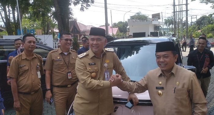 Gubernur Jambi dan Wali Kota Jambi berfoto bergenggaman tangan usai menjajal mobil listrik, Selasa (10/1/2023). (Foto Siklusjambi.id/Nasution)