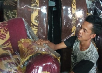 Sukandi kempis saat membungkus sofa yang dibuat nya dengan plastik. (Dok. Pribadi)